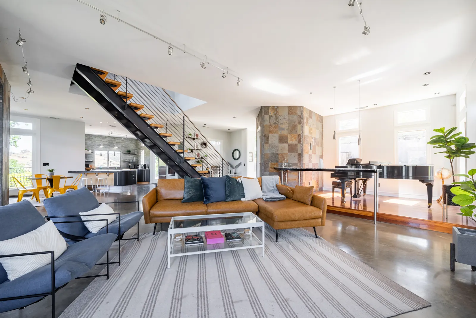Great room with sofas, the open staircase and the grand piano